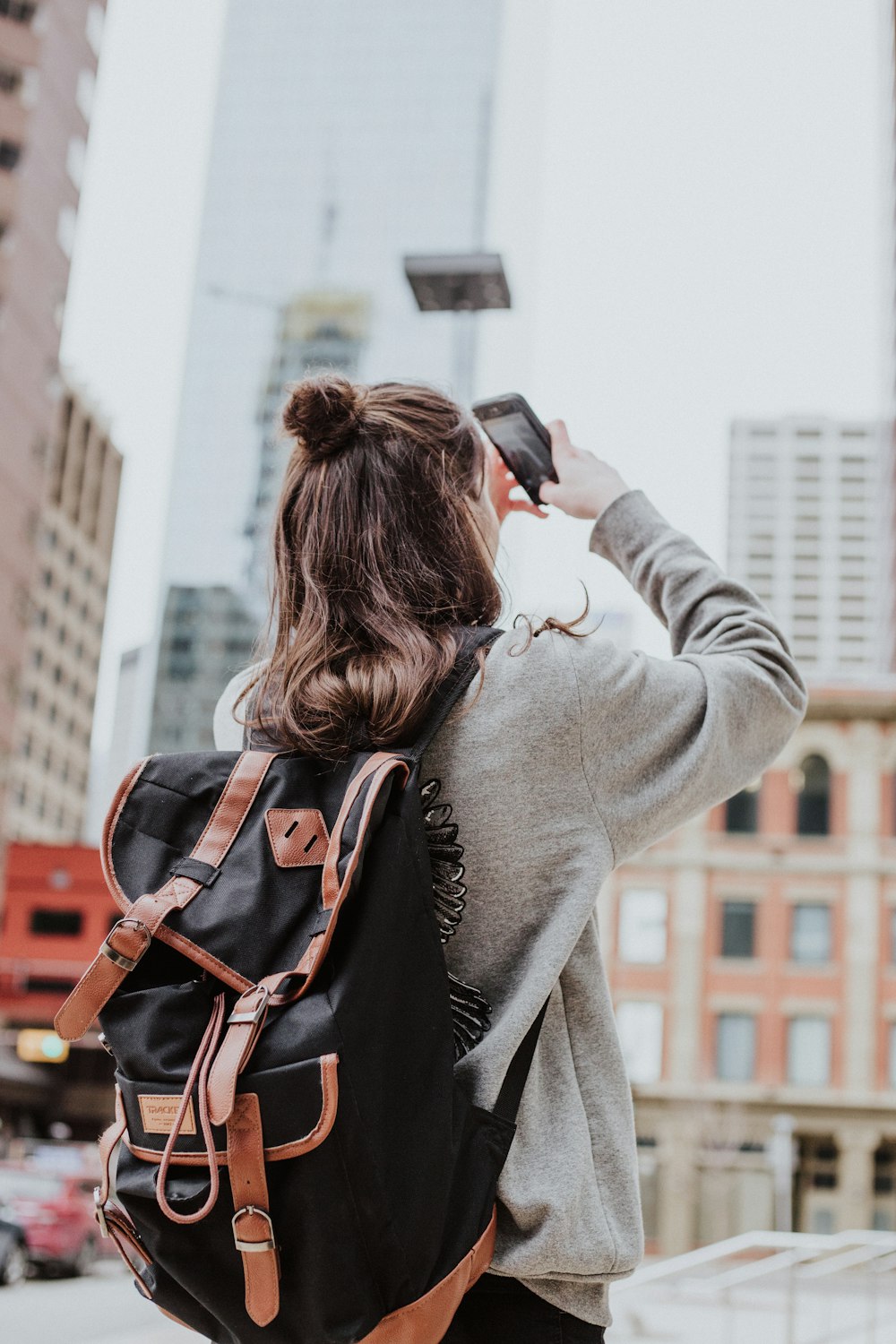 woman taking photo of high-rise building beside road