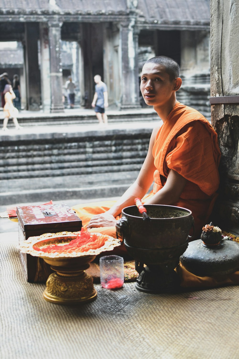 monk sitting near gray pillar