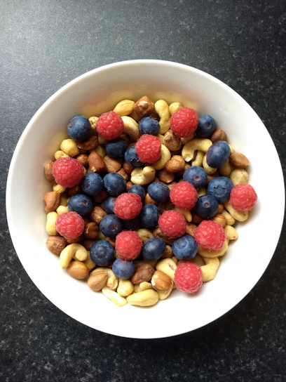 A vibrant bowl of fresh fruits and nuts on a wooden table, symbolizing wholesome nutrition.