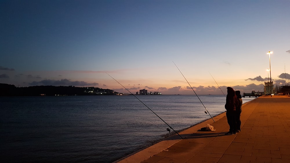 foto di silhouette di persona in piedi sul marciapiede di cemento grigio