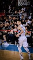 man wearing white and blue basketball jersey standing inside basketball field