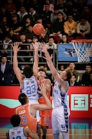 men playing basketball in court surrounded by people