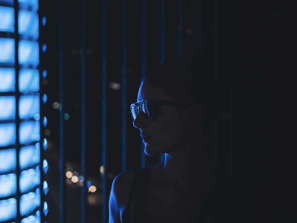 woman with sunglasses facing into blue light