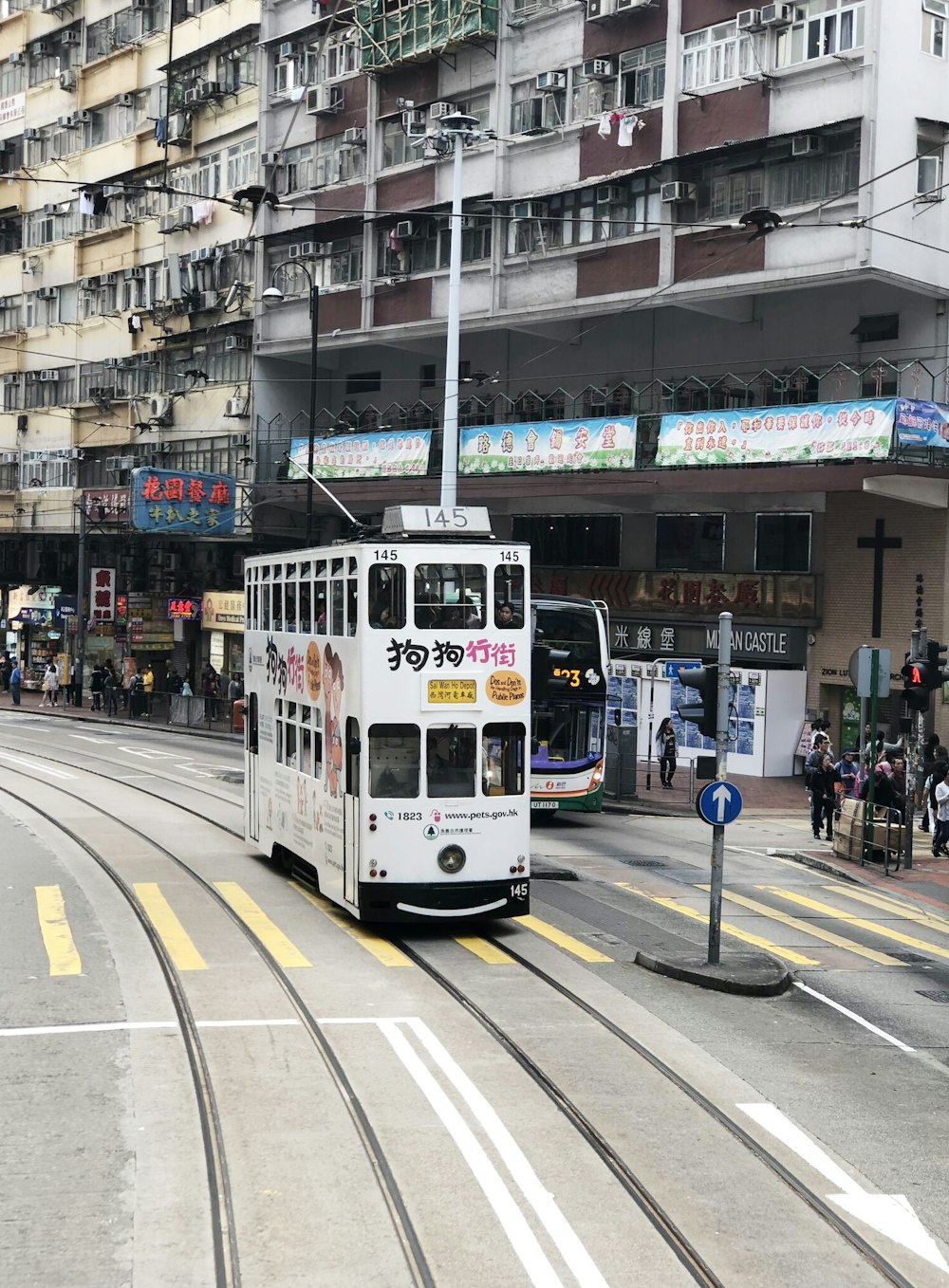 Bus à impériale blanc près d’un immeuble de grande hauteur blanc et brun pendant la journée