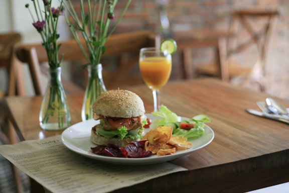 A rustic wooden table with a freshly made artisanal burger, crispy salchipapas, and a cold drink, capturing the warm and lively atmosphere of Chac Burger.