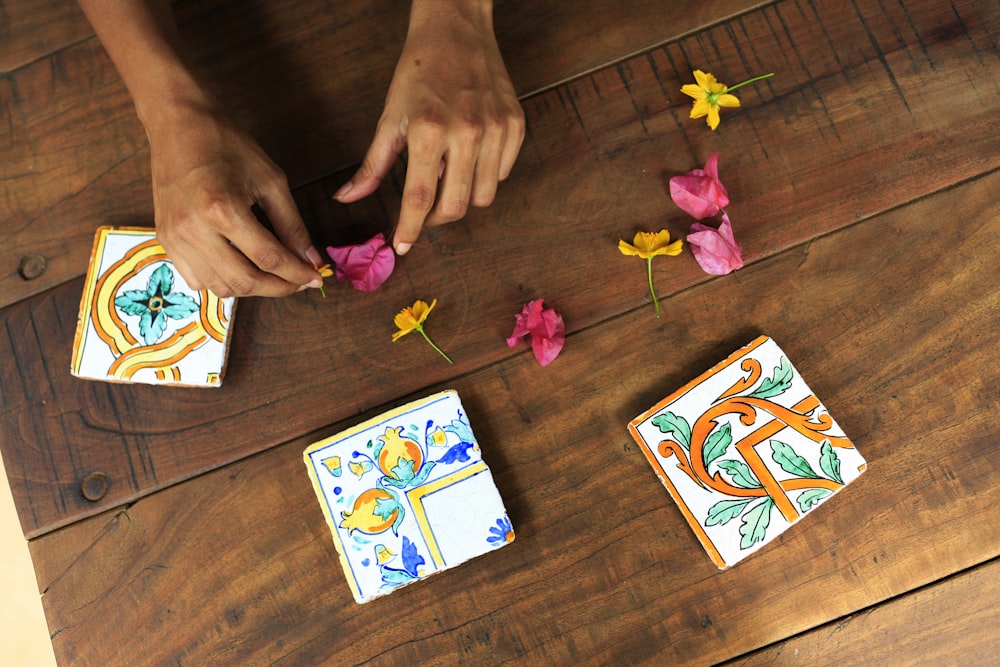 person holding pink flower petal on brown parquet floor