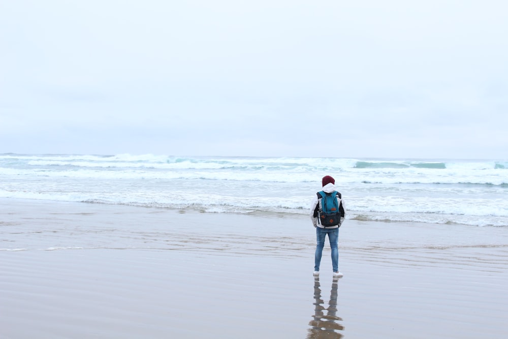 person stands in sandy beach