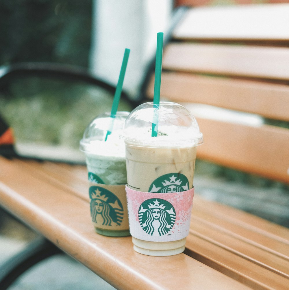 two Starbucks cups on bench