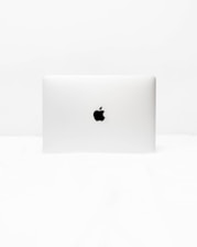 A minimalist image of a closed laptop with a distinct logo in the center. The background and surrounding area are uniformly white, emphasizing the simplicity and sleek design of the laptop.