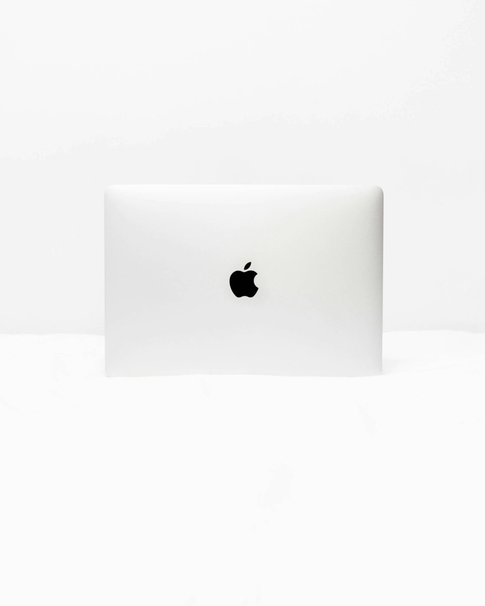 MacBook Blanc ouvert sur une surface blanche