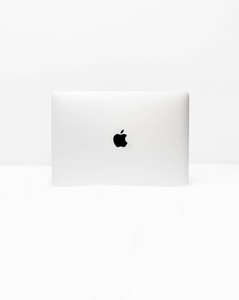 A minimalist image of a closed laptop with a distinct logo in the center. The background and surrounding area are uniformly white, emphasizing the simplicity and sleek design of the laptop.