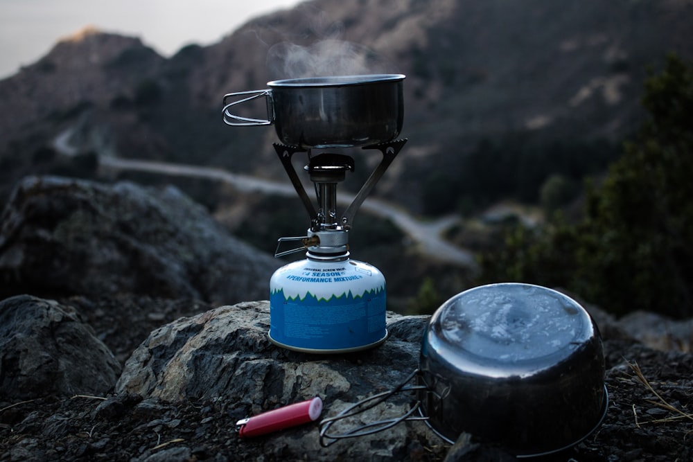 崖の上の青と灰色のキャンプ用ガスバーナーと調理鍋の選択的焦点