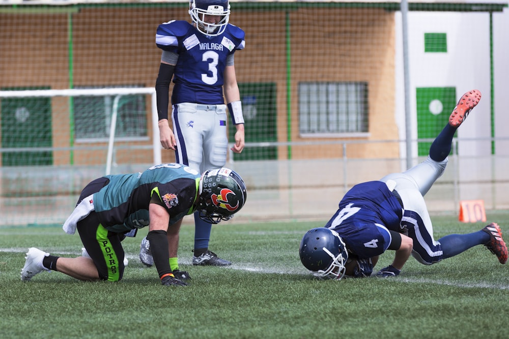 three American football standing on grass field