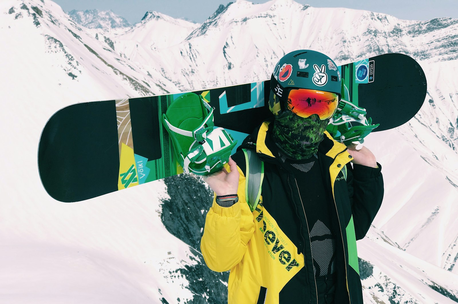 Rider holding a snowboard across their shoulders in the mountains