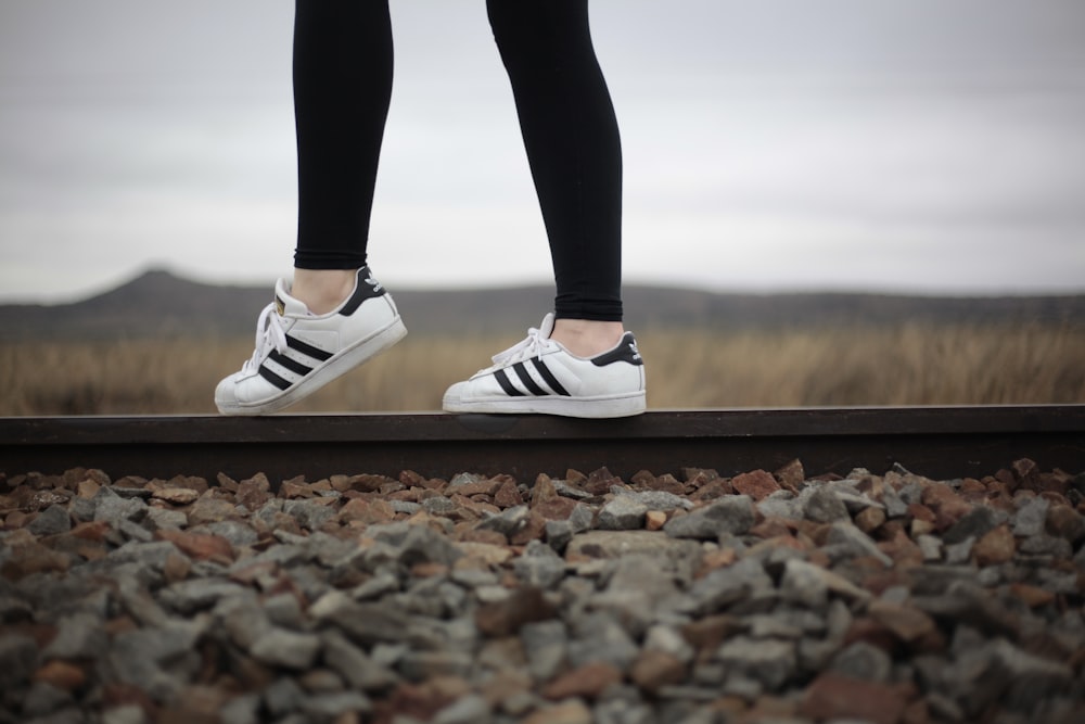 person wearing white-and-black adidas superstar