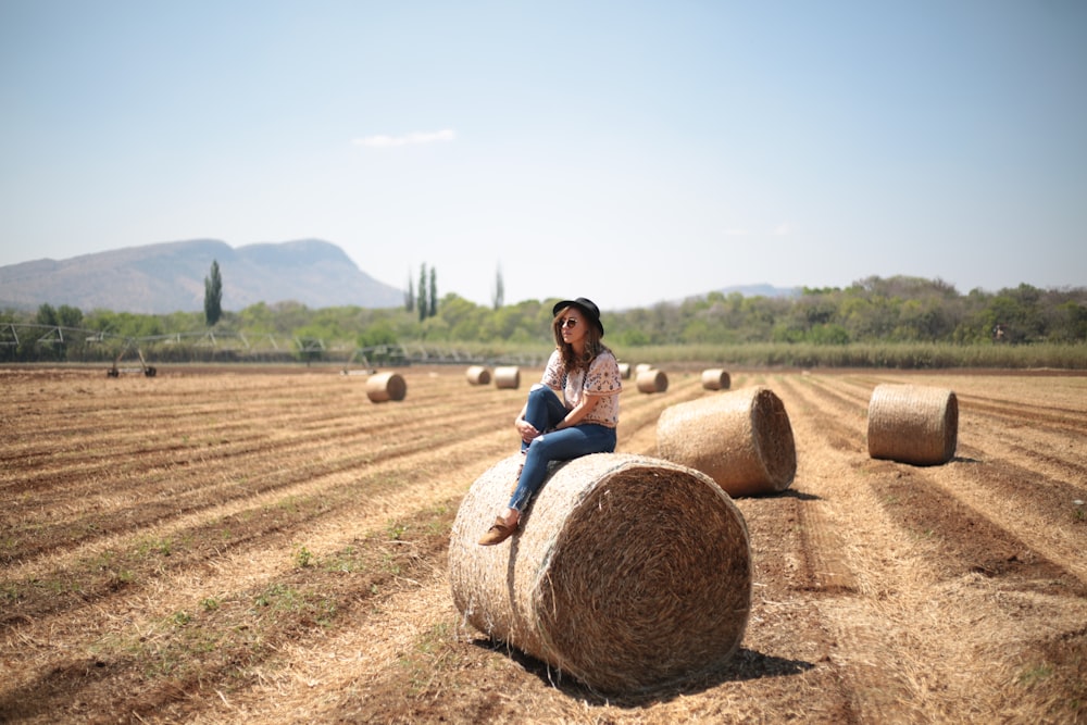 woman sitting on round hale bale