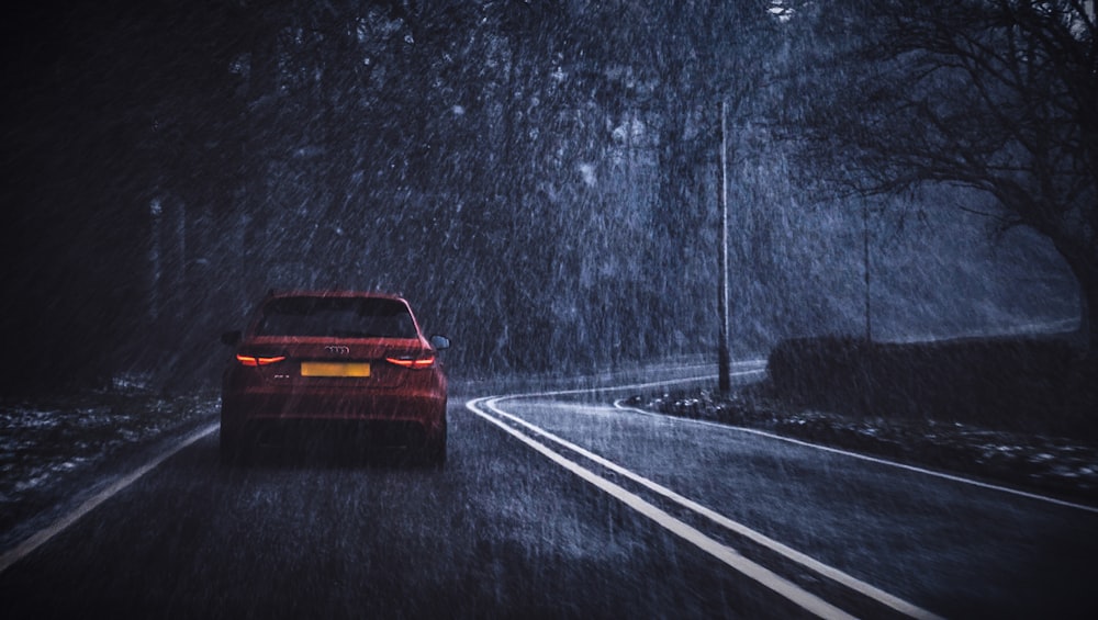 Coche rojo en la carretera mientras llueve