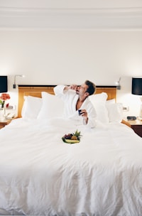 man wearing bathrobe eating on bed