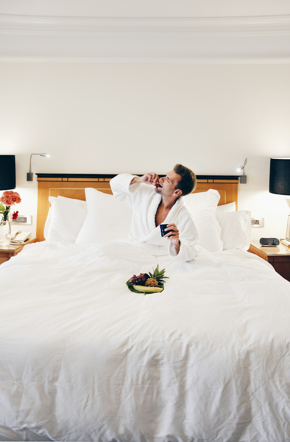 homem usando roupão comendo na cama