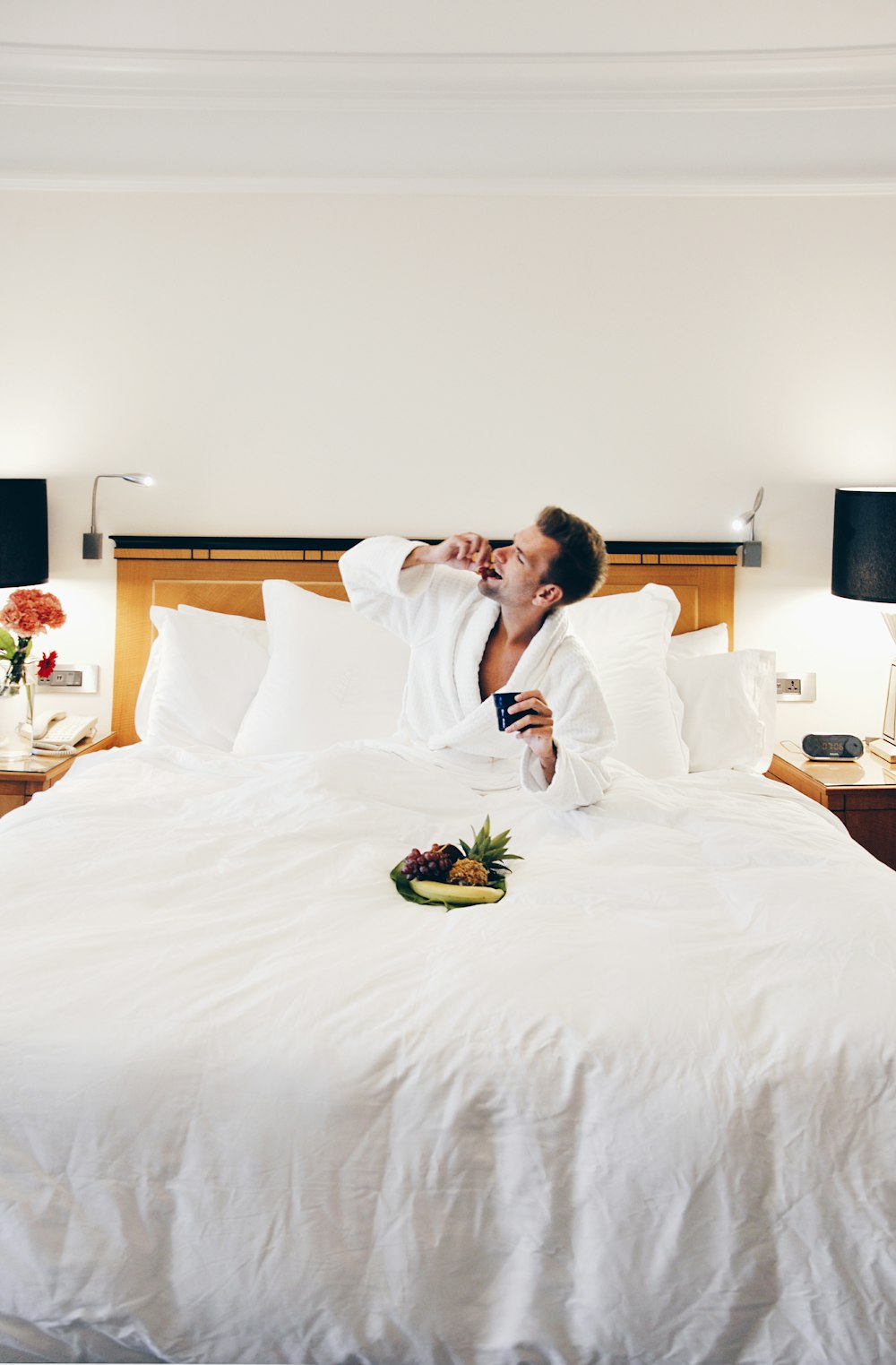 homme portant un peignoir mangeant sur le lit