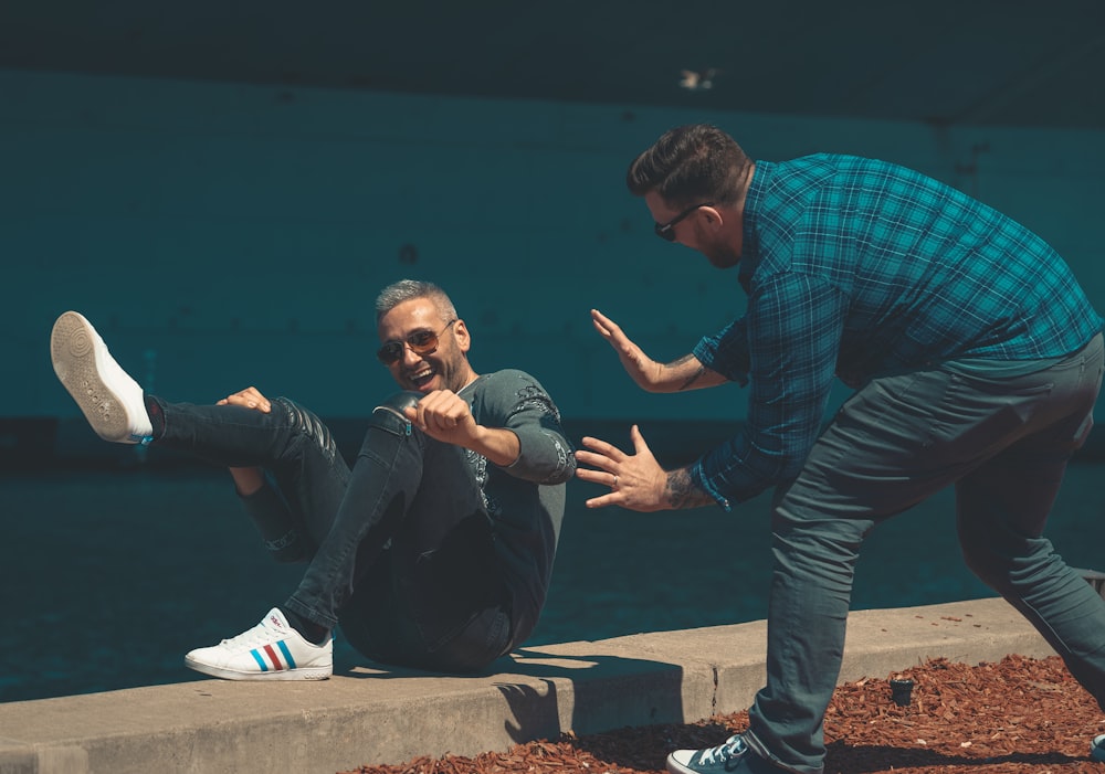 man lying on concrete near another man