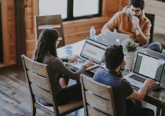 selective focus photography of woman and man using MacBook Pro on table