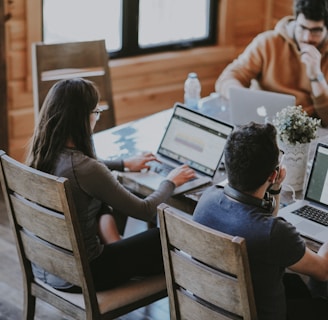 selective focus photography of woman and man using MacBook Pro on table