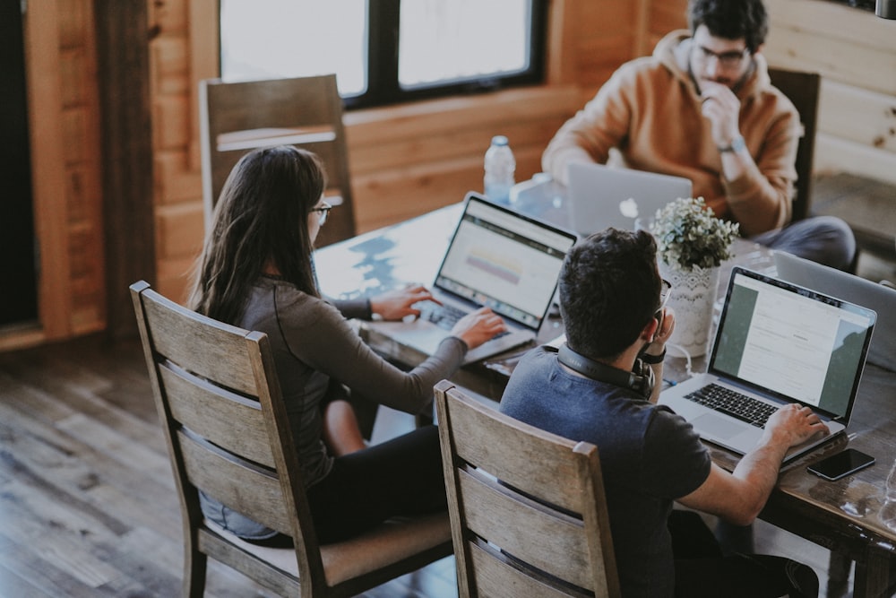 selective focus photography of woman and man using MacBook Pro on table