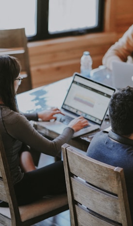 selective focus photography of woman and man using MacBook Pro on table