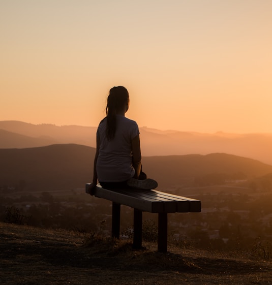 woman sitting on bench over viewing mountain