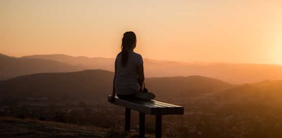 woman sitting on bench over viewing mountain