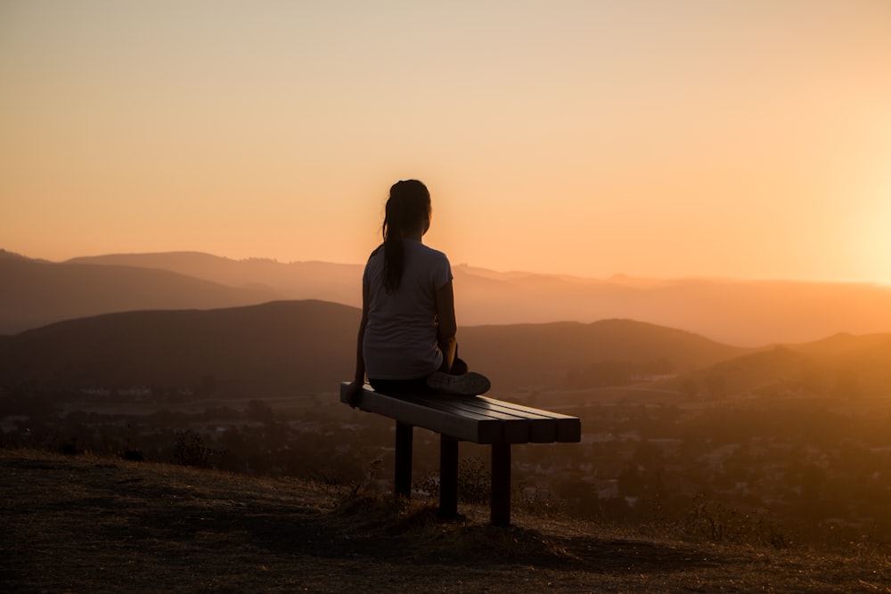 山を眺めるベンチに座る女性