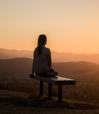 woman sitting on bench over viewing mountain