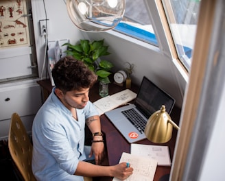 man sits while writing in front of MacBook