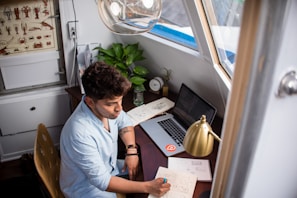 A focused entrepreneur jotting down goals in a cozy, sunlit workspace.