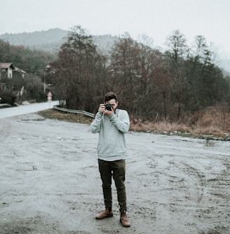 man holding camera in snow-covered road