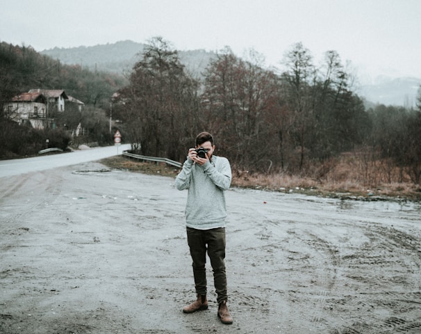 man holding camera in snow-covered road