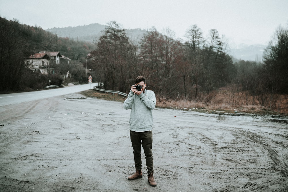 man holding camera in snow-covered road