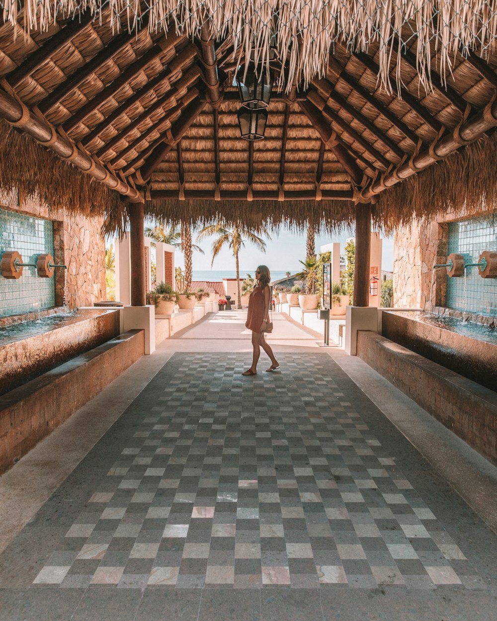 woman standing on gray pavement under nipa shed