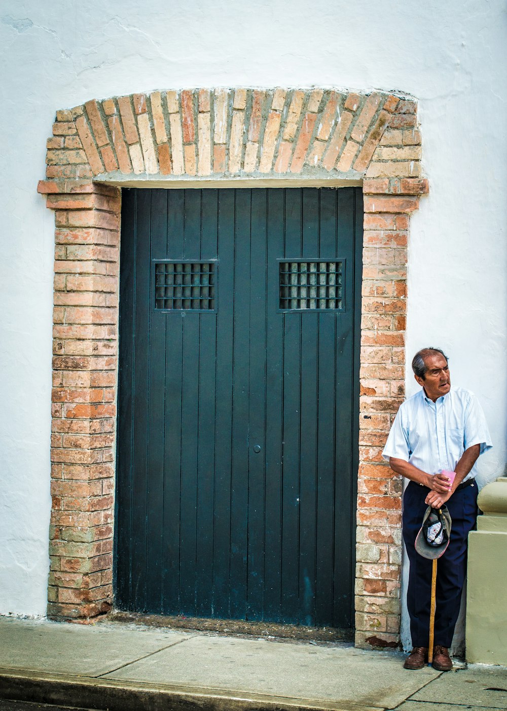 man in white shirt standing next to wooden door