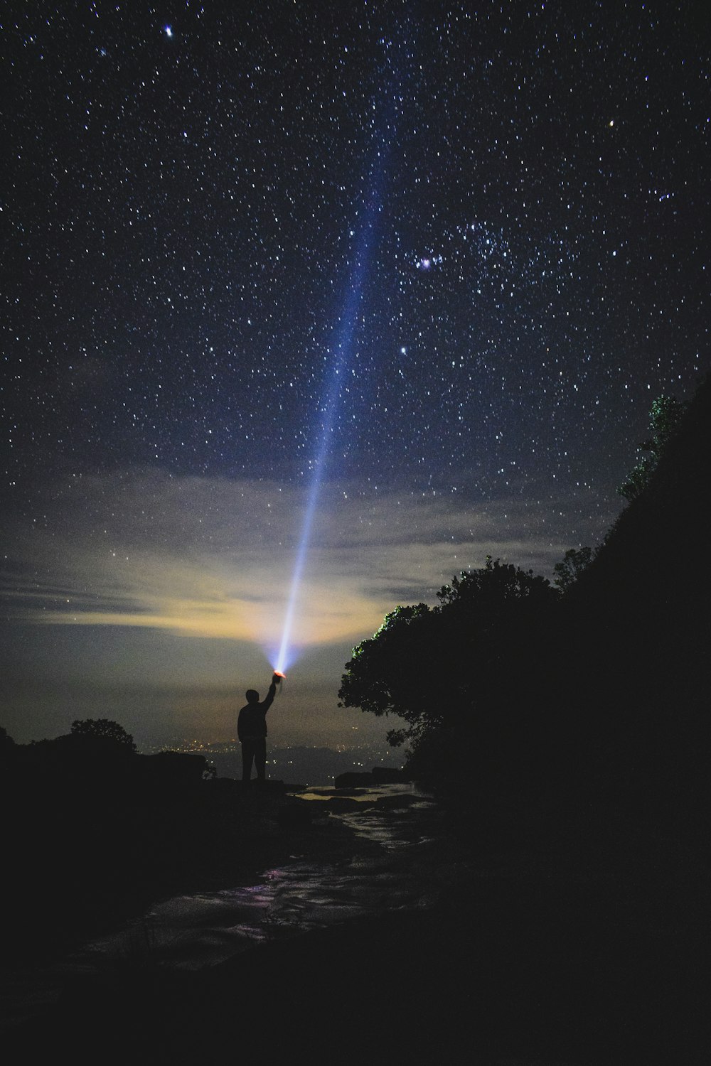 homme tenant une lampe de poche pointant vers le ciel