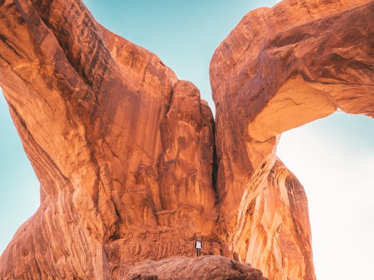 person standing under cliff during daytime in Double Arch United States