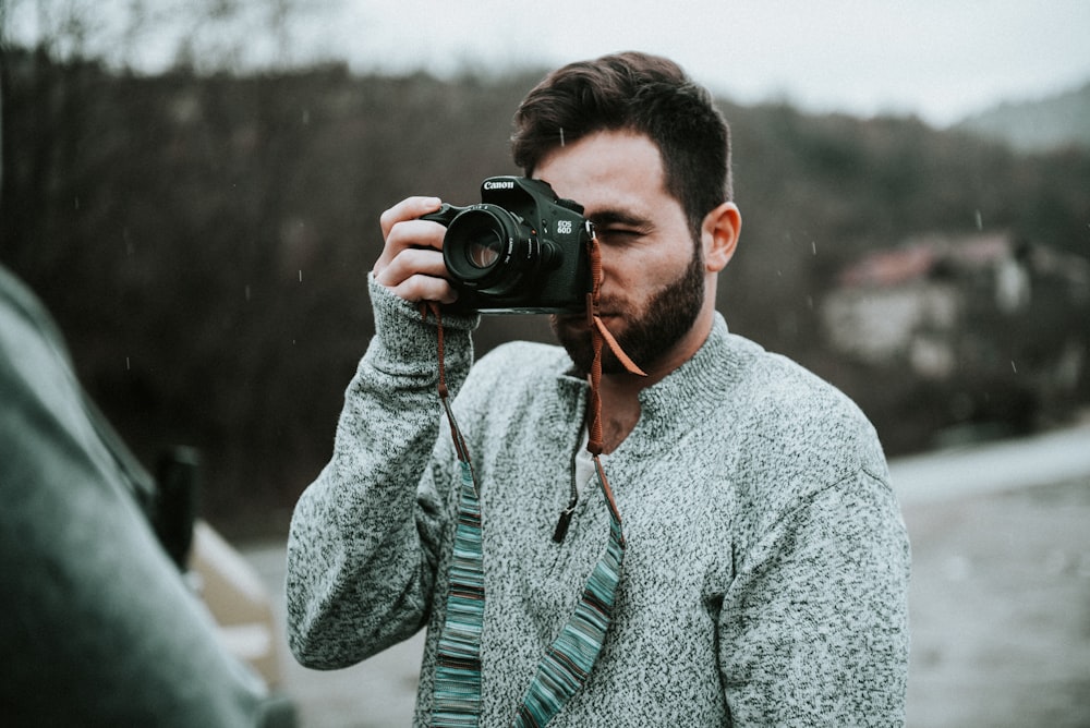 selective focus photography of man holding DSLR camera