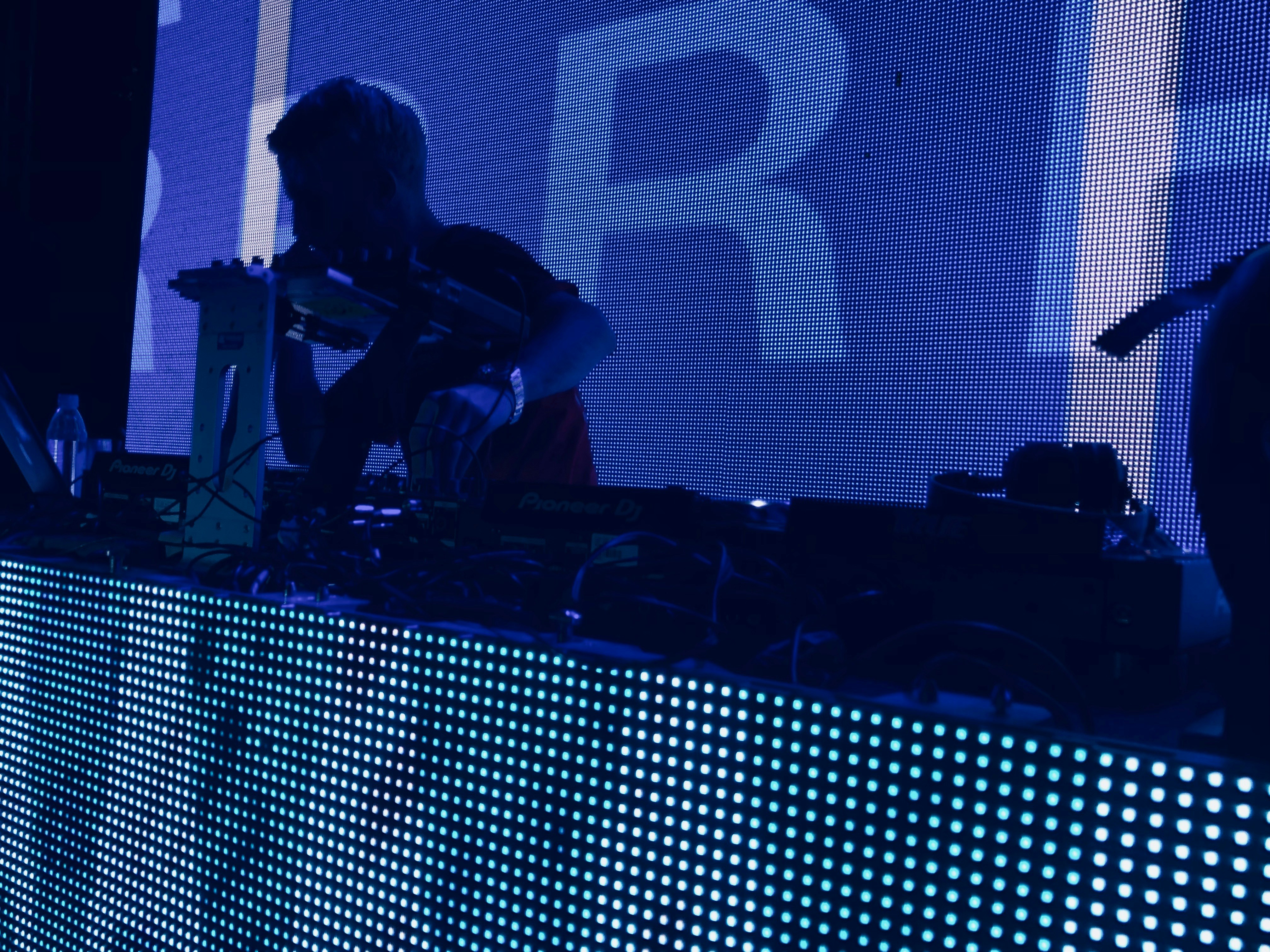 man wearing t-shirt holding DJ mixer inside dark room