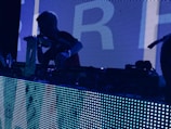 man wearing t-shirt holding DJ mixer inside dark room in Huntsville Alabama