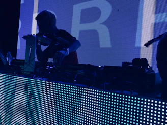 man wearing t-shirt holding DJ mixer inside dark room