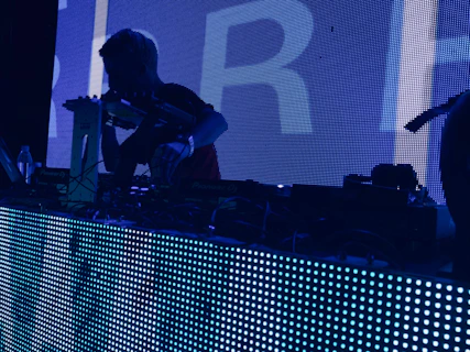 man wearing t-shirt holding DJ mixer inside dark room