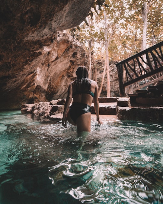 woman in bikini walking out of water inside cave in Tulum Mexico