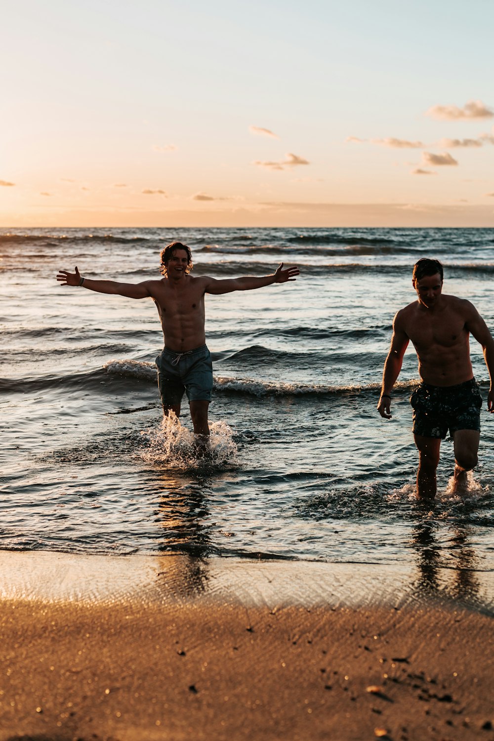 two men standing at shore during golden hour