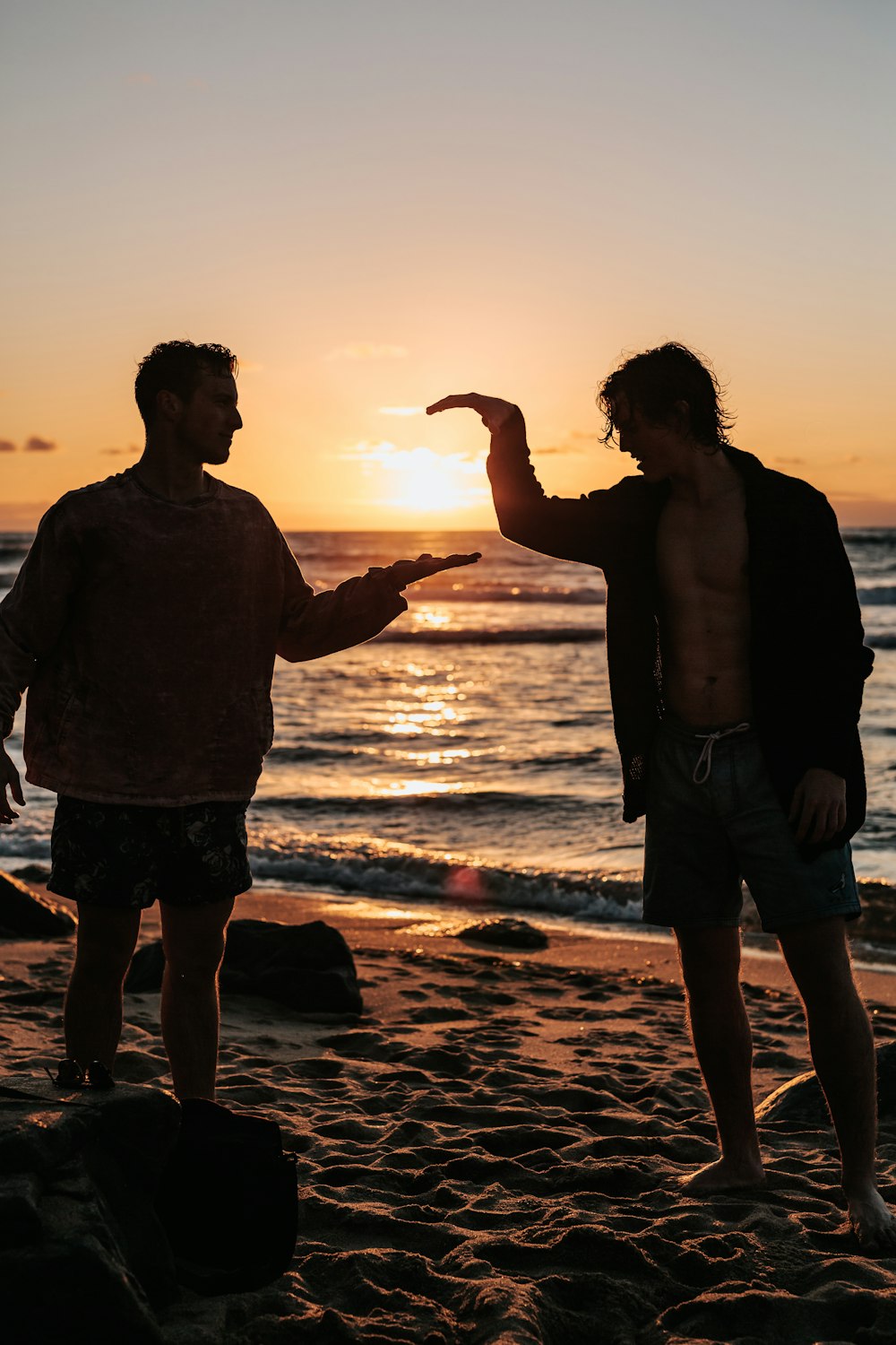 Nahaufnahme von zwei Männern, die sich bei Sonnenuntergang in der Nähe des Strandes die Hände schütteln